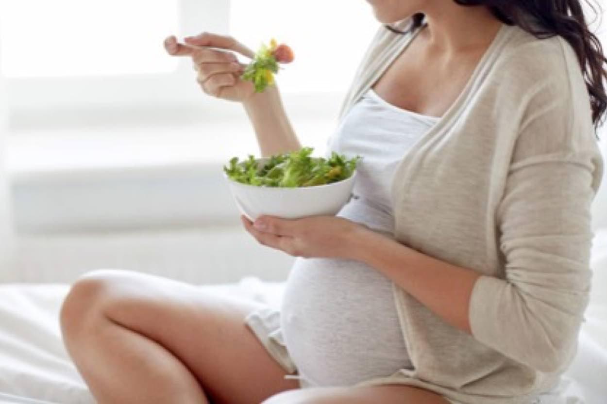 A pregnant woman eating salad